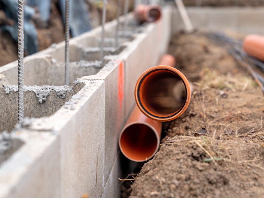 Plastic water pressure pipes being laid into a prepared trench in the ground